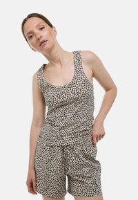 Ensemble débardeur et short en imprimé l�éopard beige, avec des taches noires et brunes, en tissu doux, et taille élastique sur le short.