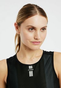 Zwart sporttop met mesh-textuur, voorzien van een ronde halslijn en een 'protest'-logo in het wit in het midden.