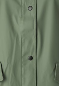 Grön vattentät jacka med slät yta, tryckknappar och sidofickor. Svarta detaljer förstärker den minimalistiska designen.