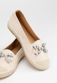 Espadrillas in suede beige con una suola media in juta intrecciata e un cluster decorativo di strass blu e trasparenti sulla punta.