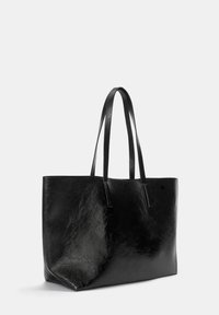 Borsa tote nera in pelle con texture liscia, fondo piatto, manici lunghi e design minimalista. Nessuna ferramenta o accentuazione visibile.