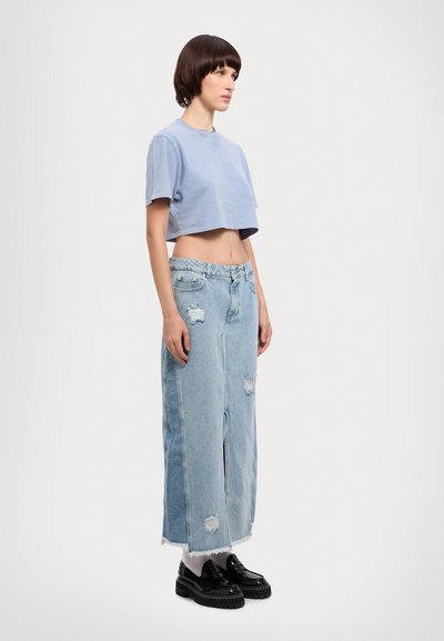 Lichtblauw cropped t-shirt, versleten lichtblauwe denim rok met rafelrand, en zwarte plateau-schoenen met details.