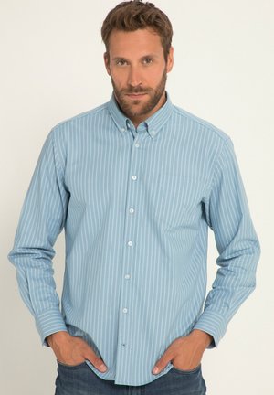 Camicia azzurra a righe con colletto a punta, maniche lunghe e taschino sul petto. Tessuto strutturato con righe bianche verticali.