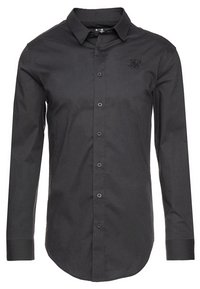 Camisa de dress de manga larga negra, hecha de una tela suave. Presenta un frente de botones, cuello con puntas y un logotipo sutil en el pecho.