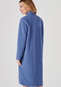 Bata larga de forro polar azul con un collar alto y mangas largas. La tela tiene una textura suave y está diseñada para proporcionar calidez.