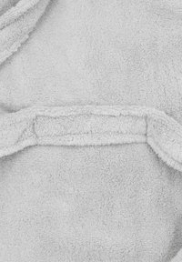 Minkštas, šviesiai pilkas frotinės medžiagos audinys su tekstūruota paviršiumi, matomi siūlės ir klostės. Lygūs kraštai be aiškių raštų ar akcentų.