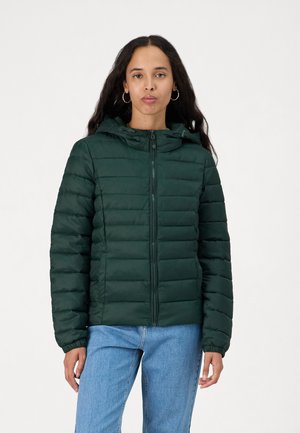 Dunkelgrüne Daunenjacke mit horizontalen Nähten, einer Kapuze und einem Reißverschluss vorne. Hat elastische Bündchen und ein tailliertes Design. Getragen mit blauen Jeans.