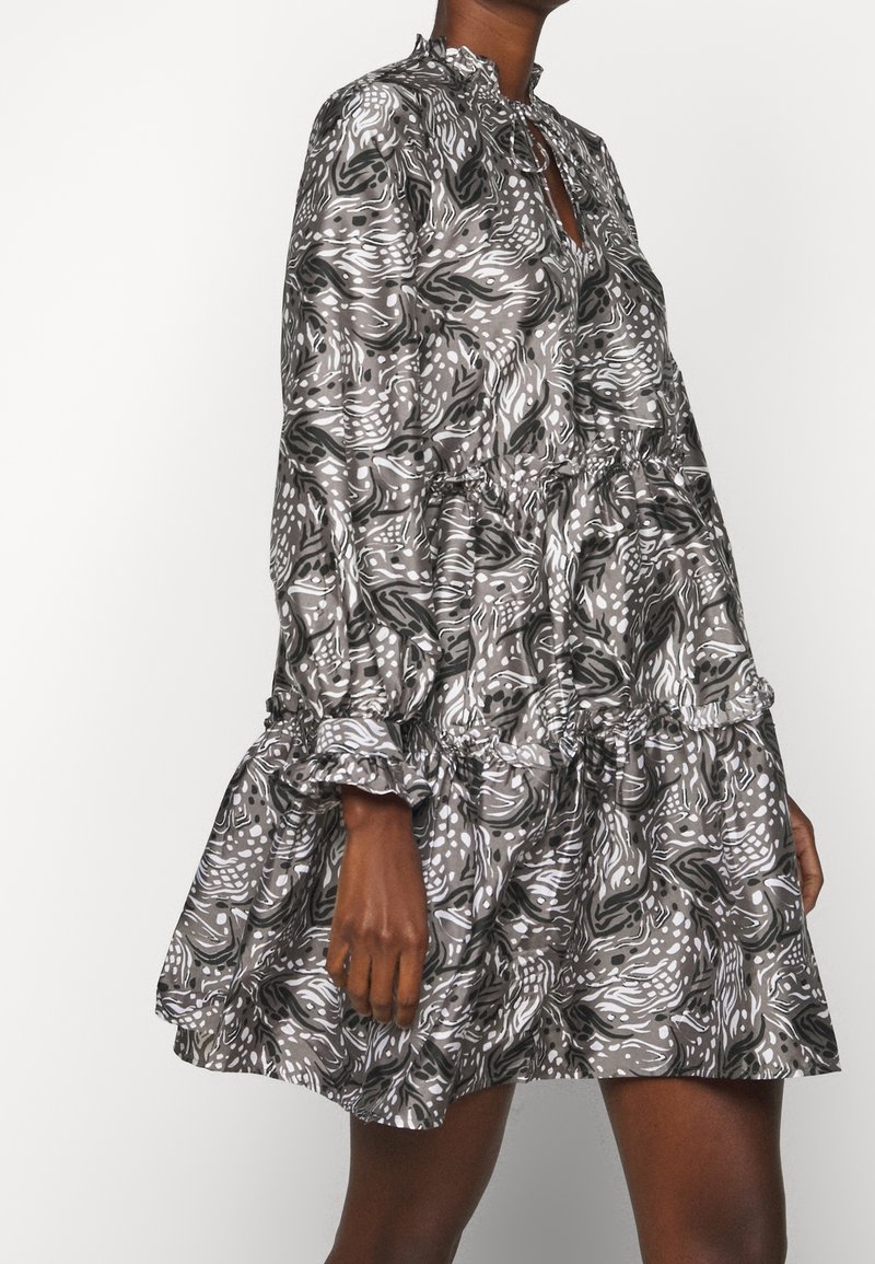 Kortärmad klänning med hög krage, som har ett virvlande mönster i grått och vitt, volang i nederkant och rynkad detalj vid midjan.