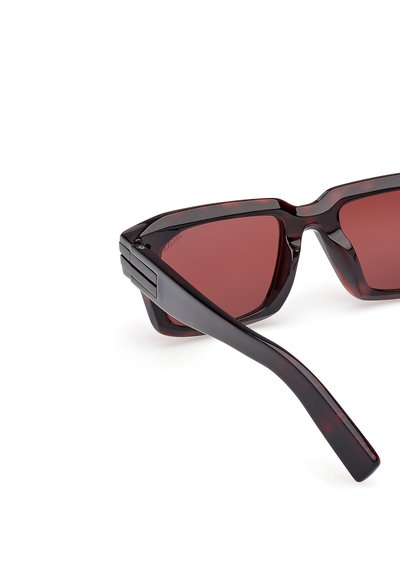 Angular sunglasses with dark tortoiseshell frames and red-tinted lenses. Features thick arms with a sleek texture and minimal hardware.
