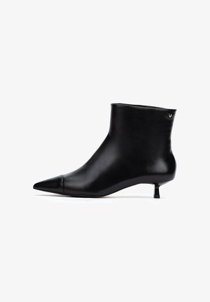 Bottine en cuir noir avec un bout pointu, un petit talon compensé et un design minimaliste. Présente un petit logo en accent à l'arrière.