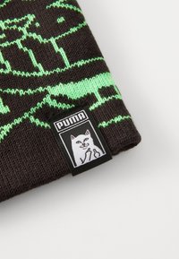 Tummanruskea neulepipo, jossa on vihreä kissagrafiikka ja musta kudottu etiketti, jossa on kissan kuva ja "PUMA"-teksti.