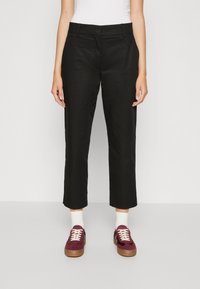 Black cropped trousers with a straight leg design, made from smooth fabric. Worn with burgundy sneakers and white socks for contrast.