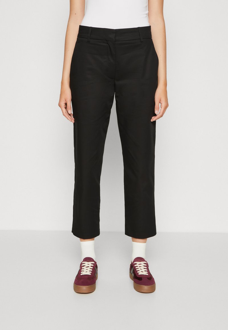 Black cropped trousers with a straight leg design, made from smooth fabric. Worn with burgundy sneakers and white socks for contrast.
