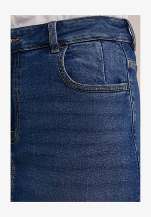 Dunkelblaue Denim-Jeans mit glatter Textur. Verfügt über eine Fronttasche, Gürtelschlaufen und kontrastierende gelbe Nähte entlang der Nähte.