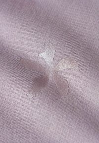 Close-up van paarse stof met een glanzend zilveren bloemenpatroon dat op het gestructureerde oppervlak is gedrukt.