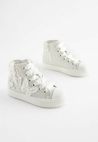 Vita högtoppsskor i glittrande silvermaterial, broderade fjärilsdetaljer och satinsnören. Har en sidodragkedja för enkel på- och avtagning.