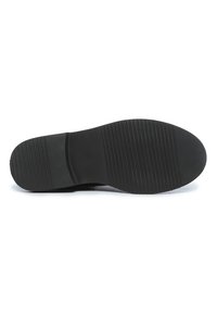 Semelle de chaussure en caoutchouc noir avec un grip texturé, présentant des lignes horizontales et verticales. Bout arrondi avec une légère élévation au niveau du talon.