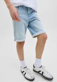 Shorts in denim azzurro chiaro con risvolti, caratterizzati da un classico design a cinque tasche. Abbinati a calze bianche e sneakers con accenti neri.
