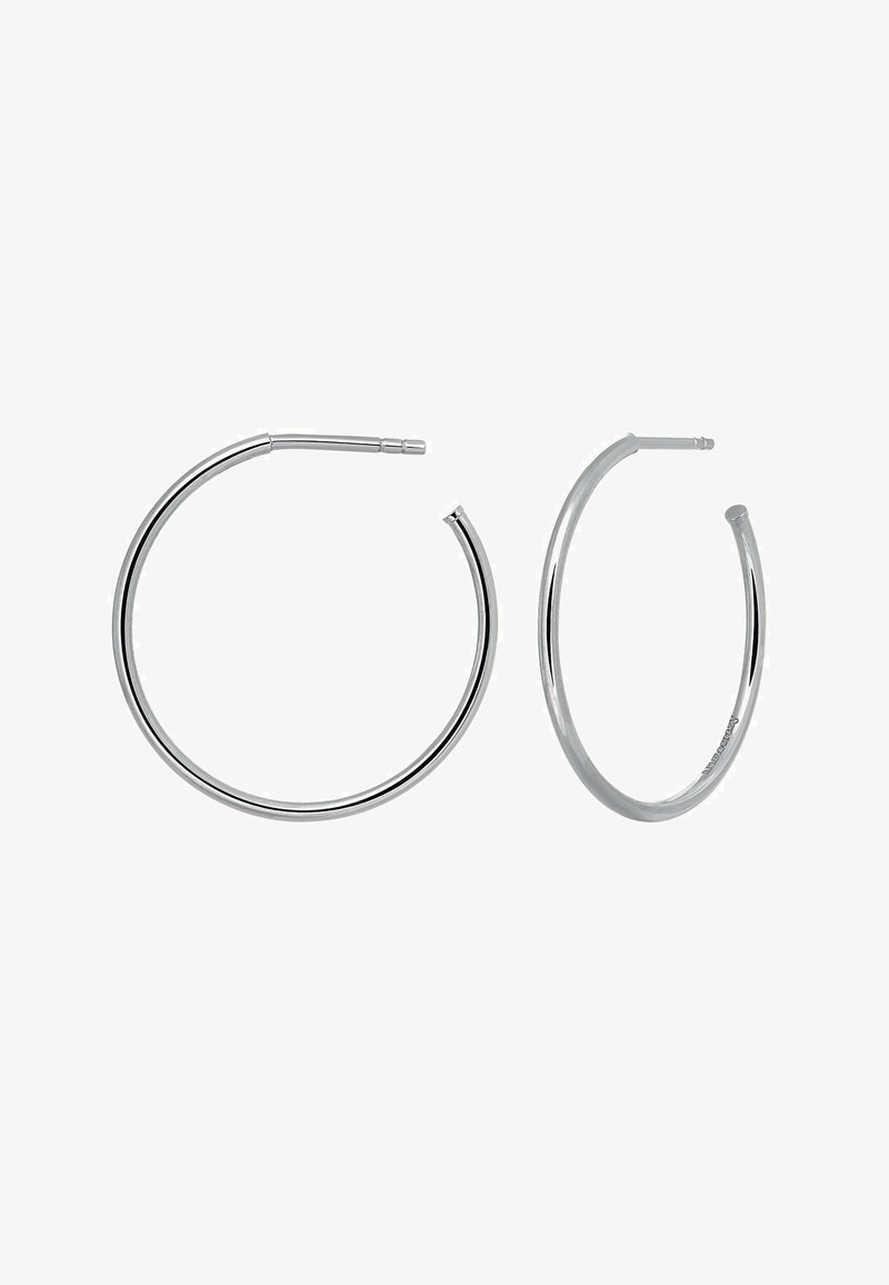 Pendientes de aro de plata con un diseño circular liso y un acabado sin costuras, y un pequeño cierre en la parte superior.