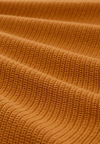 Orangeschräged Strickstoff mit einem strukturierten, wellenartigen Muster. Das Material ist weich und dick, was seine taktile Qualität verstärkt.