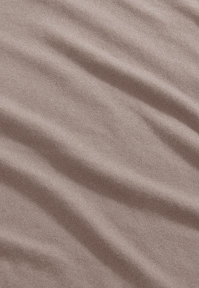 Tissu doux marron clair avec une texture fine en tricot et de délicats plis diagonaux créant des ombres et des reflets subtils.