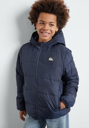Chaqueta acolchada azul marino con capucha, que cuenta con un cierre frontal, un patrón de acolchado horizontal y un parche con el logo en el pecho. Material suave y texturizado.