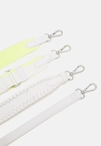 Fyra justerbara remmar i olika material: en ljusgul tyg, två vita läder med strukturerad sömnad och en slät vit. Silverfärgade beslag.