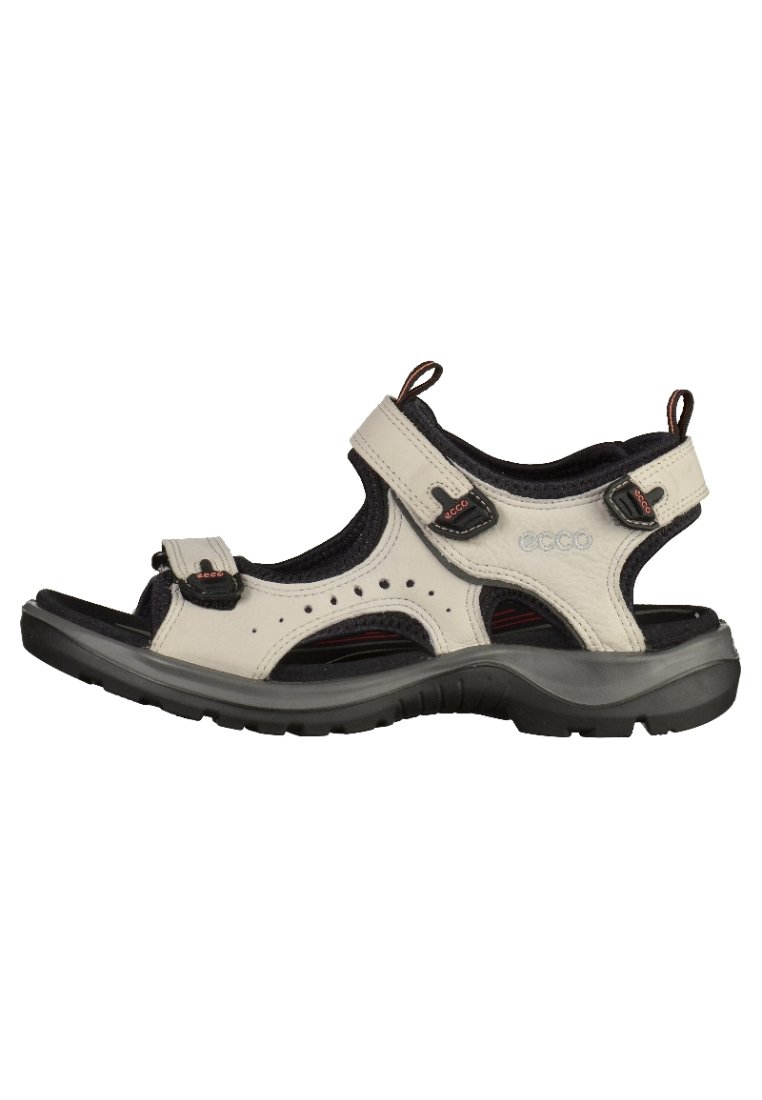 Valkgray läder sandal med justerbara remmar, svart textilfoder och en texturerad gummisula. Har perforerat mönster för andningsförmåga.