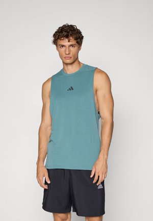 T-shirt de sport sans manches en teal, fabriqué dans un tissu doux, avec un col rond et un logo Adidas noir sur la poitrine. Associé à un short noir.