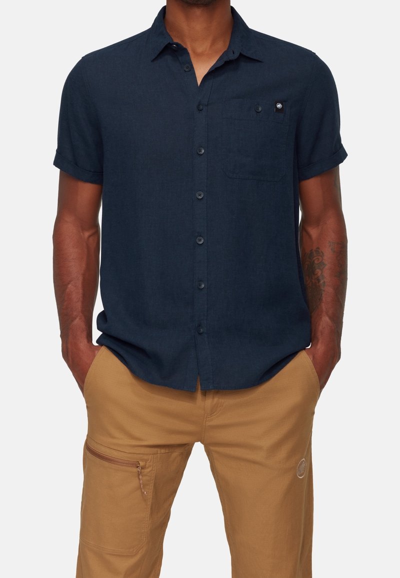 Camicia a maniche corte di colore blu navy, realizzata in tessuto testurizzato, con taschino sul petto e un piccolo logo ricamato sulla tasca.