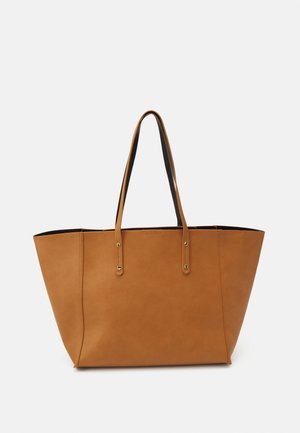 Jasnobrązowa skórzana torba typu tote z długimi podwójnymi rączkami i prostym przeszyciem na białym tle.