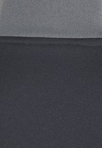 Twee panelen stof met een lichtgrijze bovensectie en een donkerblauwe ondersectie. Beide gebieden hebben een textuur van gebreid materiaal.