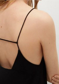 Černý top bez rukávů s tenkými ramínky, s hlubokým V výstřihem vzadu. Hladká látka vytváří minimalistický design. Žádné viditelné vzory nebo akcenty.