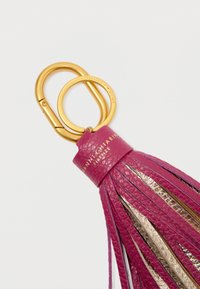 Fuchsia skinnøkkelknippe med gullhardware, med metalltrådsdetaljer og preget merkebokstaver på et skinnbånd.
