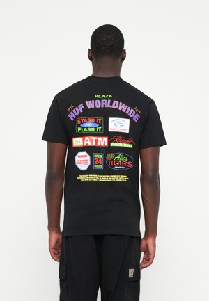 Black cotton t-shirt featuring colorful text graphics on the back, including "HUF WORLDWIDE" and various square label designs.
