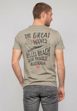T-shirt à manches courtes khaki avec un graphique de vagues et du texte. Le dos comprend "LES GRANDES VAGUES", "Belles Beach" et "Australie".