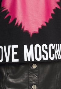 Schwarzes T-Shirt mit großem pinken Grafikdesign in der Mitte, darunter in fetten weißen Buchstaben "LOVE MOSCHINO" gedruckt.