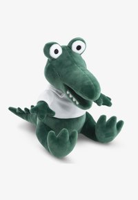 Πράσινο λούτρινο παιχνίδι κροκόδειλος με μεγάλα λευκά μάτια, λευκό πουκάμισο και υφή με λέπια, με μαλακό, στρογγυλεμένο σώμα και εμφανή δόντια.