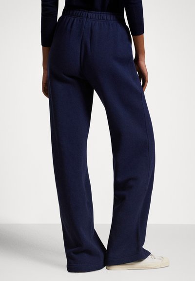 Granatowe spodnie dresowe z elastycznym pasem, luźnym krojem i miękką fakturą, posiadające szerokie nogawki i mankiety na końcach.