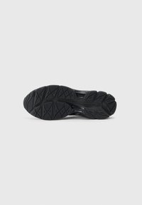 Black athletic shoe sole with intricate tread design, featuring traction patterns and a smooth, flexible rubber texture.