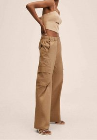 Pantalons cargo beiges avec une coupe large, dotés de deux grandes poches latérales, d'une taille élastique et fabriqués en tissu en mélange de coton durable.