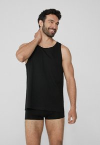 Schwarzes Tanktop aus glattem Material, mit lässigem Schnitt und weiten Armausschnitten. Kombiniert mit schwarzen Boxershorts, die ein minimalistisches Design aufweisen.