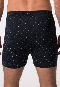 Černé boxerky vyrobené z měkké tkaniny, se malým bílým geometrickým vzorem a elastickým pasem pro pohodlí.