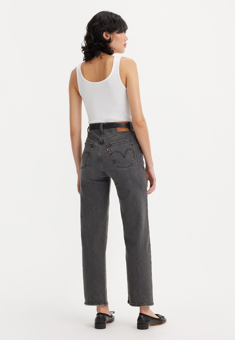 Jeans en denim noir taille haute avec une coupe droite, comportant des poches arrière et un patch en cuir sur la taille. Texture lisse, sans motifs.