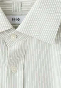 Camisa de algodón en verde claro con finas rayas verticales, con cuello clásico, cierre de botones y textura suave. Marca: MNG.