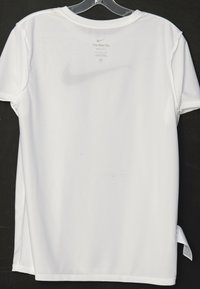 Camiseta blanca Nike Dri-FIT exhibida en un perchero. Cuenta con cuello redondo, mangas cortas y aberturas laterales. Textura suave con el logo de Nike impreso en la parte posterior.