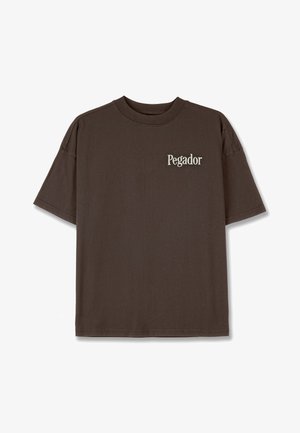 Brown cotton t-shirt with a crew neck, short sleeves, and a small white "Pegador" logo on the chest. Smooth texture, relaxed fit.