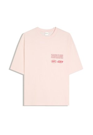 T-shirt rose clair à manches courtes avec texte rouge et logos imprimés sur la poitrine gauche. Le texte inclut des phrases sur l'état d'esprit et le mouvement.