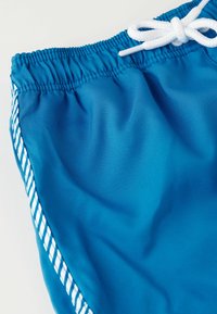 Blue swim shorts made of smooth fabric with a drawstring waistband and white accents along the sides, featuring a textured woven pattern.