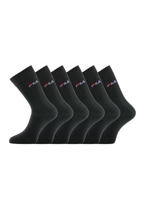 Six chaussettes de travail noires avec le logo FILA en blanc et rouge sur le bord, disposées côte à côte sur un fond blanc.